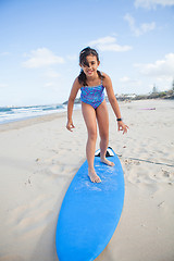 Image showing Cute young girl standing on surfboard