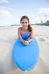 Image showing Cute young girl lying on surfboard