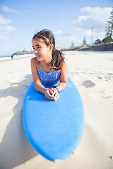 Image showing Cute young girl lying on surfboard