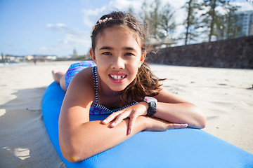 Image showing Cute young girl lying on surfboard