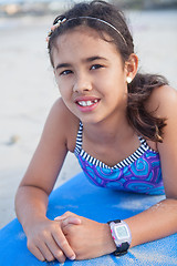 Image showing Cute young girl lying on surfboard