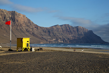 Image showing lifeguard chair red flag in s  rock stone sky cloud beach  pond 