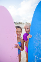 Image showing Two happy young girls holding surfboards at beach