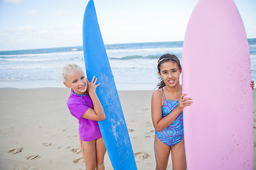 Image showing Two happy young girls holding surfboards at beach