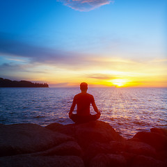 Image showing Young man practices yoga on the beach at sunset