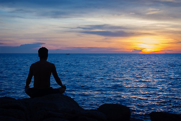 Image showing Young man practicing yoga on ocean shore