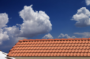 Image showing Roof tiles, snowy slope and blue sky with clouds