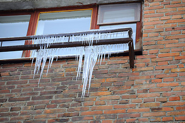 Image showing Big icicles at a window, against a brick wall.