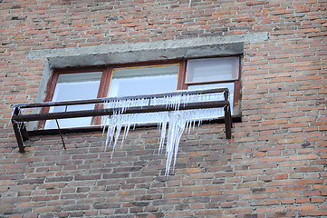 Image showing Big icicles at a window, against a brick wall.