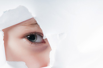 Image showing Child eye looking through a hole in paper