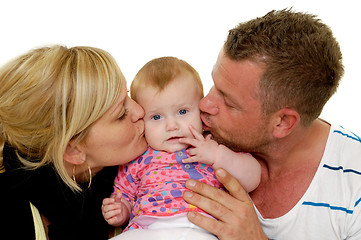 Image showing Mother and father are kissing baby