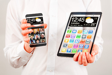 Image showing Smartphone and tablet with transparent screen in human hands.