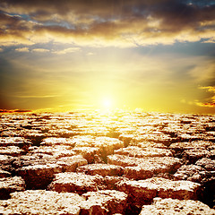 Image showing cracked desert close up and sunset over it