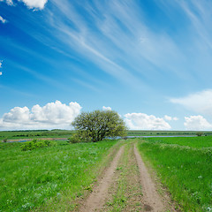 Image showing dirty road in green field and blue sky with clouds