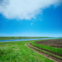 Image showing green field and road under cloudy sky in evening