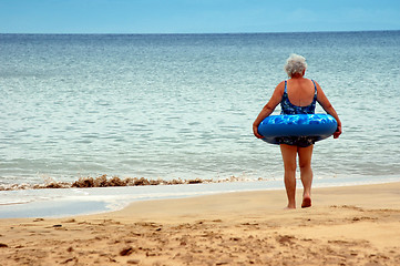 Image showing an old woman to enter in the sea with a buoy