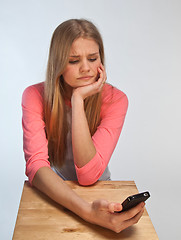 Image showing Scandinavian cute young girl looking irritated at her phone