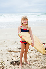 Image showing Smiling young girl holding surfboard on beach