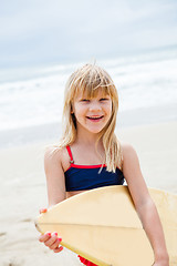 Image showing Happy young girl with surfboard on beach