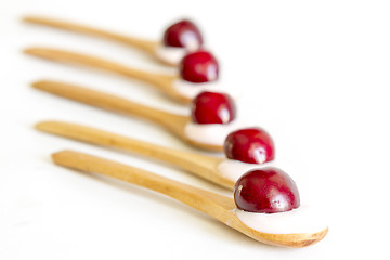 Image showing Wooden spoon is with yogurt and cherries