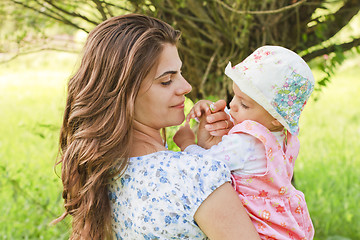 Image showing Baby girl with her mother giving a flower