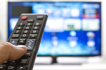 Image showing Smart tv and hand pressing remote control