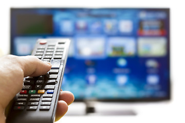 Image showing Smart tv and hand pressing remote control