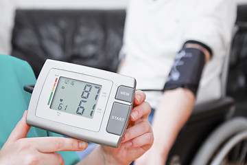 Image showing Blood pressure check for young adult in wheelchair.