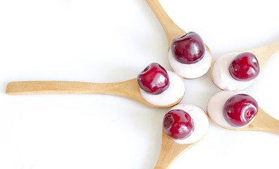 Image showing Wooden spoon is with yogurt and cherries