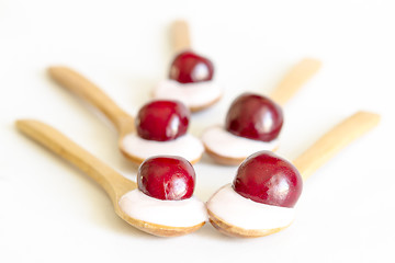 Image showing Wooden spoon is with yogurt and cherries