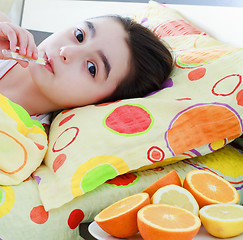 Image showing Sick little girl with a thermometer in bed