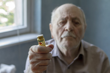 Image showing old man holding pills