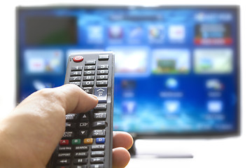 Image showing Smart tv and hand pressing remote control