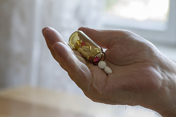 Image showing old man holding pills