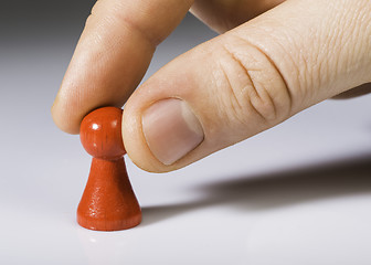 Image showing Hand holding red pawn on white background