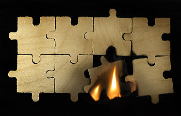 Image showing Burning wooden puzzle on dark background.