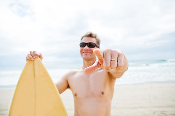 Image showing Smiling man with surfboard at beach pointing with finger