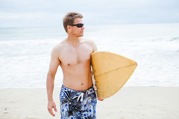 Image showing Relaxed looking man walking with surfboard at beach