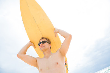 Image showing Man resting surfboard on head at beach