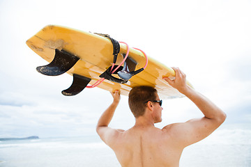 Image showing Man resting surfboard on head at beach