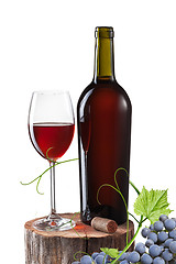 Image showing Glass of red wine, bottle and grape on stump isolated on white