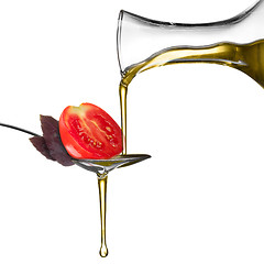 Image showing Pouring oil on spoon with basil and tomato isolated on white