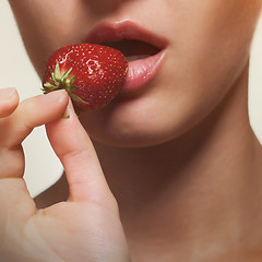 Image showing Young woman biting strawberry isolated on white