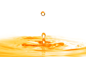 Image showing drop falling into orange water with splash isolated on white