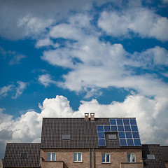 Image showing New houses with solar panels on roof under blue sky and clouds