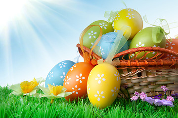 Image showing color easter eggs in basket against blue sky and clouds