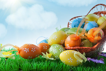 Image showing color easter eggs in basket against blue sky and clouds