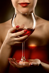 Image showing woman in red holding wine glass and smiles