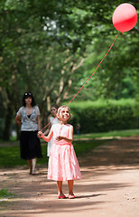 Image showing Little girl looks up at balloon held aloft
