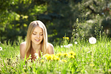 Image showing Spring girl lying on the field of dandelions